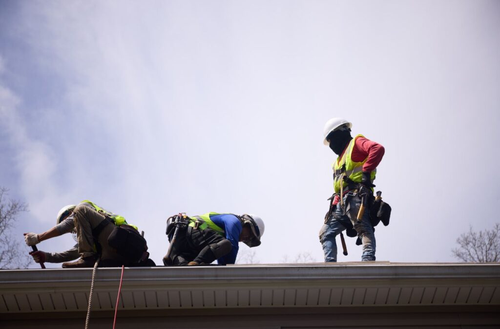 Roofing specialist inspecting flat roof seams and drainage areas with professional repair tools. Flat Roof Repair Near Me.